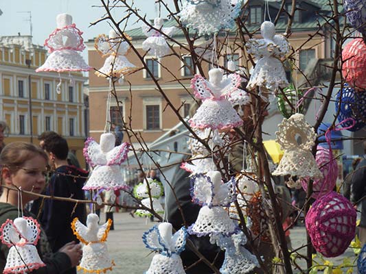 Zamość rynek a na nim stoisko jarmarczne z aniołkami robionymi na szydełku